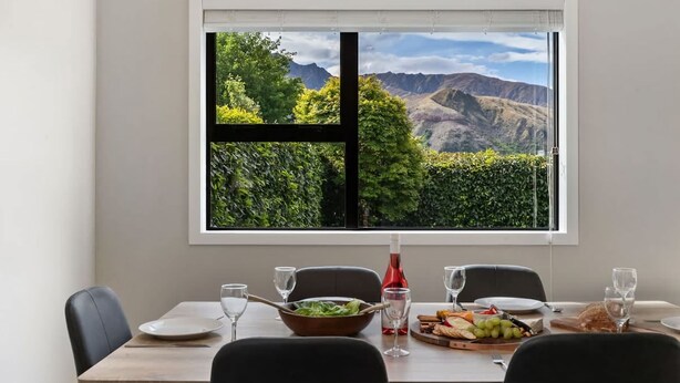 Una mesa de comedor con vistas a las montañas a través de una ventana.