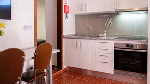 A compact kitchen with white cabinets, a built-in oven, and a stainless steel range hood. - GuestReady - Machico sea view residence - A (Machico)