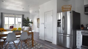 A modern kitchen with a stainless steel refrigerator, a dining area with a table and chairs, and a view of the outdoors through large windows. - NEW Colorful + Spacious 3BD/2BA Home in the ❤️of Mill Valley
- Fully remodeled  (Mill Valley)