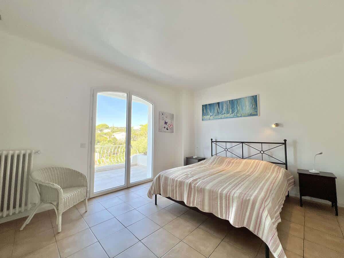 Une chambre comprenant un lit, une chaise, un radiateur et une porte-fenêtre coulissante donnant sur un espace extérieur.