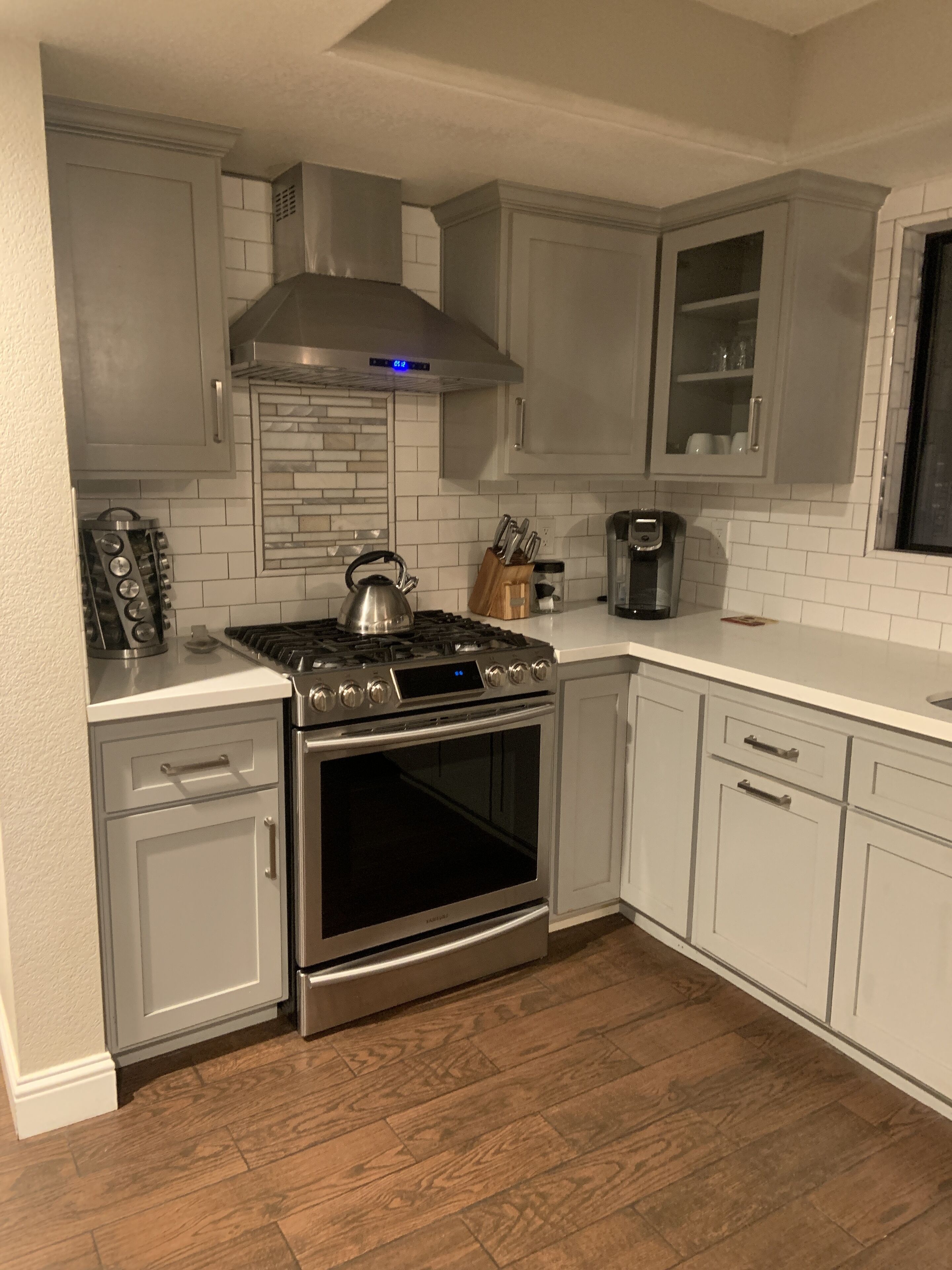 A kitchen with white cabinets, a stainless steel stove, and a built-in oven.