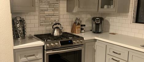 A kitchen with white cabinets, a stainless steel stove, and a built-in oven.