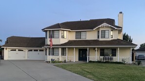 Ein zweistöckiges Haus mit einer Haustürgarage, einer überdachten Veranda und einem gepflegten Rasen.