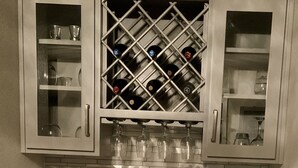 Eine Küche mit Weinkühler, Weingläsern, einem gerahmten Zitat und einer grünen Flasche.
