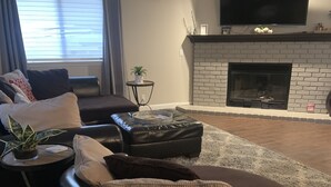 Ein Wohnzimmer mit Kamin, einer Couch, einem Couchtisch und einem Fernseher.
