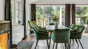 Un comedor con mesa y sillas, ventanas amplias y un ventilador de techo.