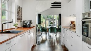 Una cocina moderna con armarios blancos, encimera de madera y horno Bosch.
