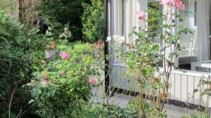 Een tuin met bloeiende rozen en een houten terras.