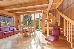 Un intérieur en bois comprenant un coin repas, un canapé et un escalier.