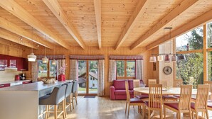 Ein Holzblockhaus-Interieur mit Küche, Essbereich und großen Fenstern.