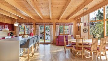 Ein Holzblockhaus-Interieur mit Küche, Essbereich und großen Fenstern.