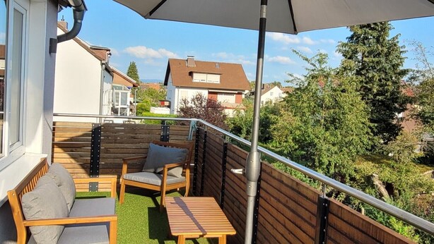 A patio with artificial grass, wooden furniture, and a large umbrella. - Apartment 'Apartement Hangarstein' with Balcony and Wi-Fi (Kassel)