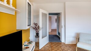A hallway with a TV, a door, a plant, and a sofa. - Apartment 'Apartement Hangarstein' with Balcony and Wi-Fi (Kassel)