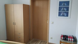 A bedroom with a wardrobe, a bed, a small stool, and a wall-mounted picture. - "Kijas" holiday flat with private terrace and WLAN (Wismar)