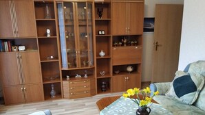 A living room with a wooden cabinet, a sofa, a coffee table with a vase of flowers, and a patterned tablecloth. - "Kijas" holiday flat with private terrace and WLAN (Wismar)