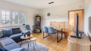 Een moderne woonkamer met een bank, stoelen, een eettafel, een open haard en een televisie.