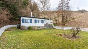 Een huis met een witte gevel, blauwe luiken en een stenen fundering.