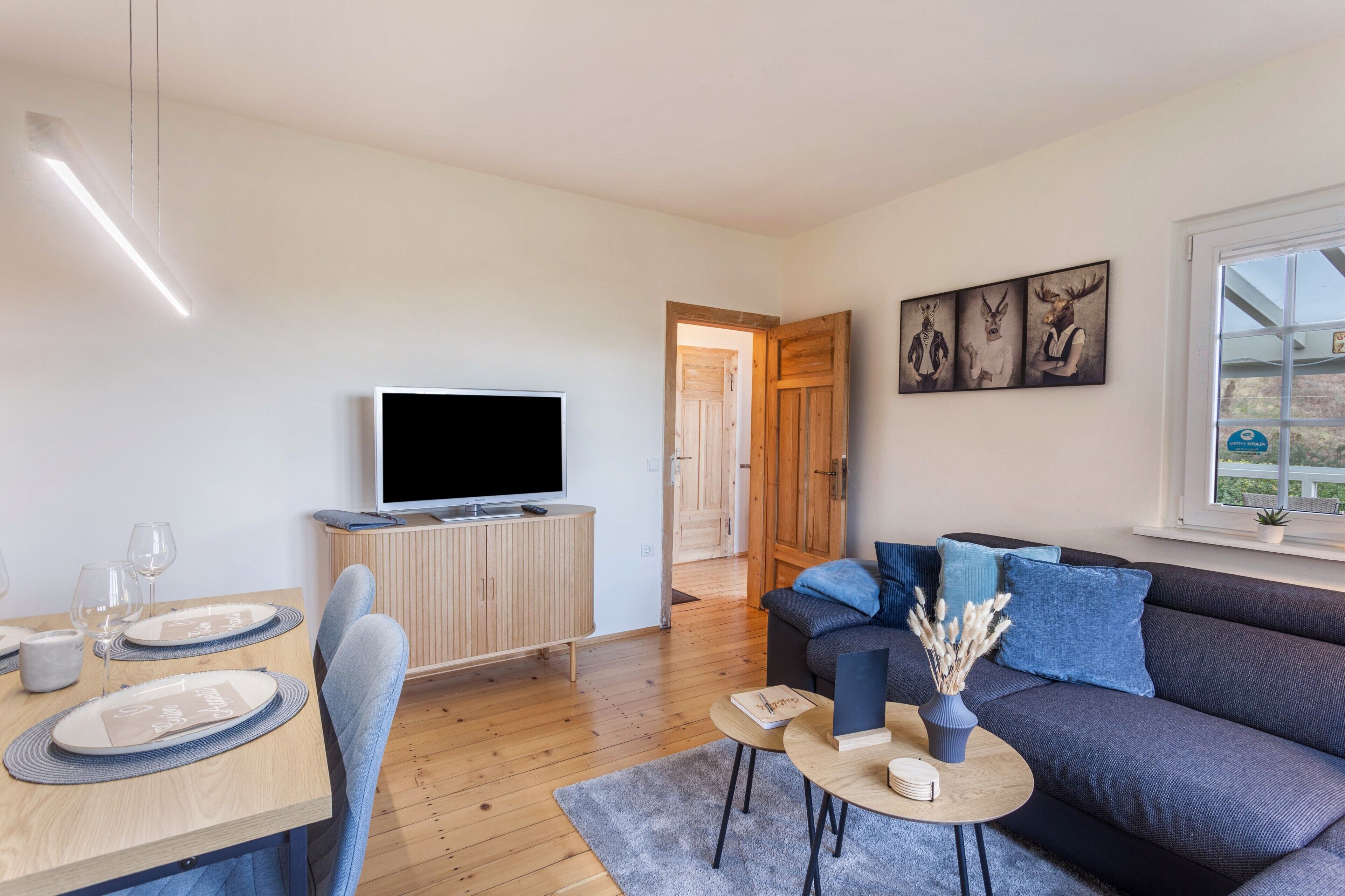 Una sala moderna con televisor de pantalla plana, una mesa de comedor de madera y un sofá.
