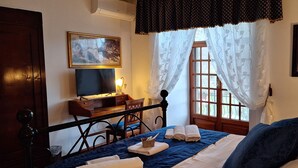 A bedroom with a bed, a desk, a television, and a window with curtains. - L'Antica Sosta (Corciano)