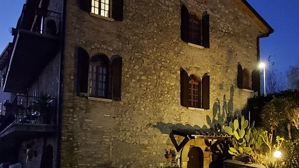 A stone building with a balcony and a small garden area with plants. - L'Antica Sosta (Corciano)