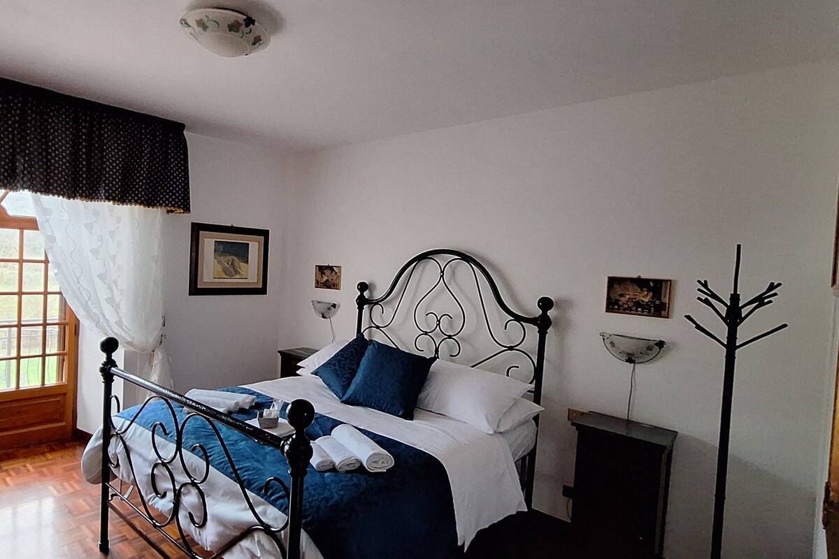 Une chambre à coucher avec un lit, une chaise, un porte-manteau et une fenêtre avec des rideaux.