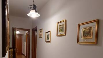 En hall med trägolv, inramade tavlor på väggarna och en hängande lampa.