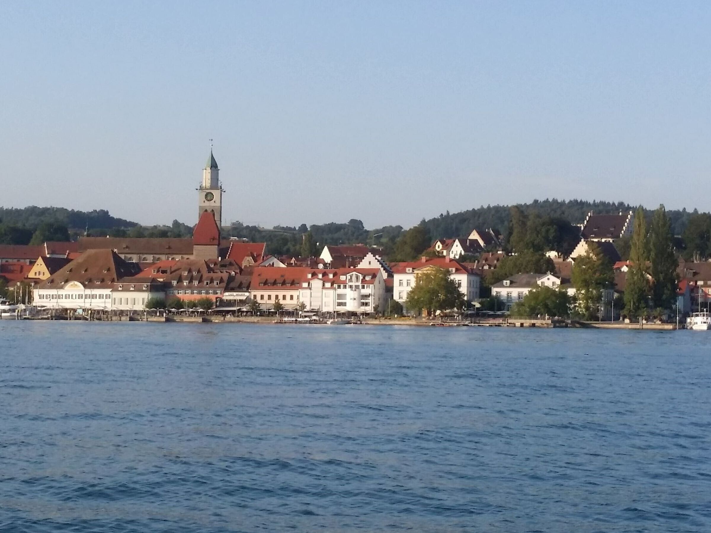 Una cittadina sulle rive del fiume, con edifici storici, un’imponente torre dell'orologio e un tratto d'acqua tranquilla.