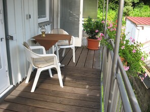 A wooden deck with a table and chairs, a potted plant, and a railing.