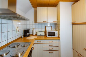 Una cocina con estufa, microondas, tostadora y armarios de madera.