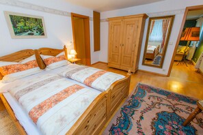 A bedroom with a wooden bed, a nightstand, a wardrobe, and a mirror.