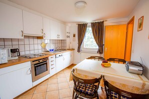 A kitchen with white cabinets, a stove, a sink, and a dining table with chairs.