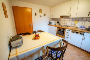 A compact kitchen with white cabinets, a microwave, a stove, and a dishwasher.