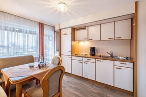 Une cuisine de taille réduite avec un coin repas, comprenant une table, des chaises et une machine à café.