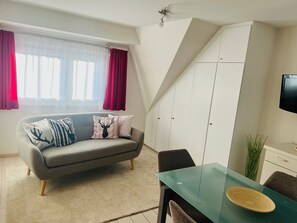 A modern living room with a grey sofa, a glass dining table, and a white wardrobe. - 7 Ferienwohnung Erika, 35qm mit 1 Schlafzimmer für max. 3 Personen (Höchenschwand)