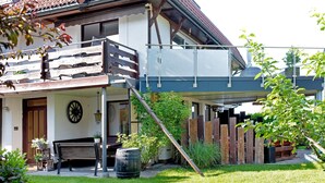 Une maison à deux étages avec un balcon, une clôture en bois et un jardin.