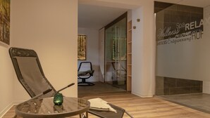 Un intérieur moderne avec une cloison en verre, un plancher en bois et un espace salon comprenant une table en verre et des chaises en métal.