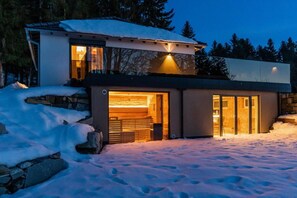 Uma casa moderna com fachada de pedra, grandes portas de vidro e entrada coberta.