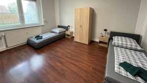 A bedroom with a bed, a wardrobe, a desk, and a window. - Apartment 'Das Grüne Haus' with Shared Terrace and Shared Garden (Finsterwalde)