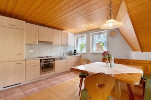 A kitchen with wooden cabinets, a stove, and a dining table with chairs.