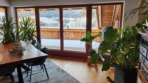 A dining area with a wooden table, chairs, and potted plants.