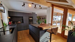 A modern kitchen with a central island, built-in appliances, and wooden beams on the ceiling.