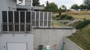 Un bâtiment doté d’un balcon, d’un espace extérieur couvert aménagé en coin salon et d’un mur en béton.