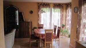 Un coin repas comprenant une table, des chaises, un meuble et une plante en pot.