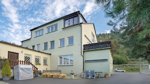A two-story building with a garage, a covered outdoor seating area, and a car parked in the driveway.