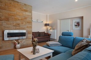 A living room with a stone wall, a fireplace, a blue sofa, a white coffee table, and a lamp.