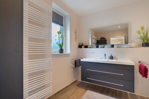 A modern bathroom with a large window, a sink with a mirror, and a towel rack.