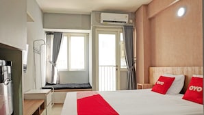 Una camera d'albergo con un letto, una scrivania, una sedia, una finestra e un climatizzatore.