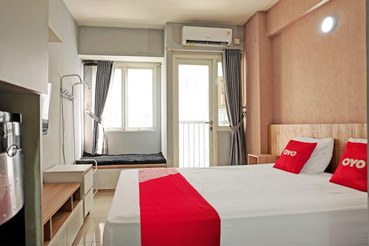 Ein Hotelzimmer mit Bett, Schreibtisch, Stuhl, Fenster und Klimaanlage.