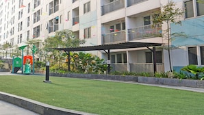Un edificio residenziale con balconi, un'area giochi e un prato curato.