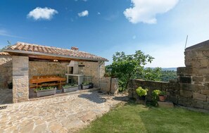 A stone building with a tiled roof, a stone bench, and potted plants.
